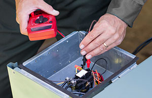 Person using volt meter on a heating unit