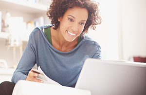 Woman reviewing paperwork looking at laptop