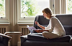 Woman sitting on sofa reviewing paperwork