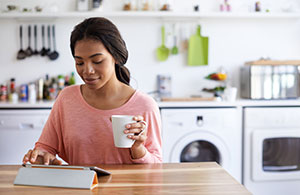 Woman sitting at kitchen table looking at iPad