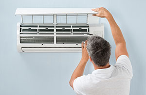Man cleaning ductless AC unit